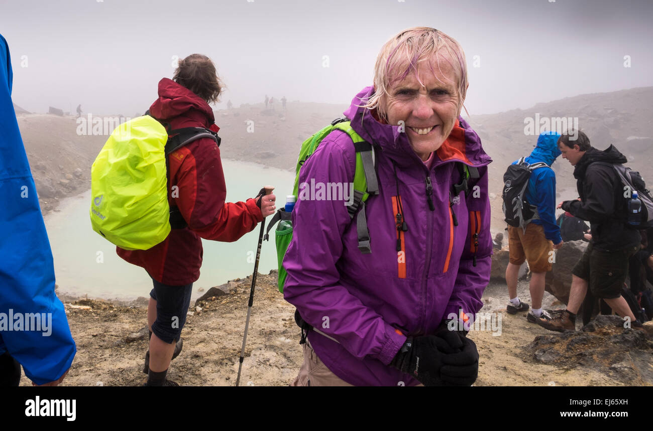 Soaking Wet walkers sul Tongariro alpine crossing sosta presso il lago blu in condizioni climatiche estreme, Nuova Zelanda. Foto Stock