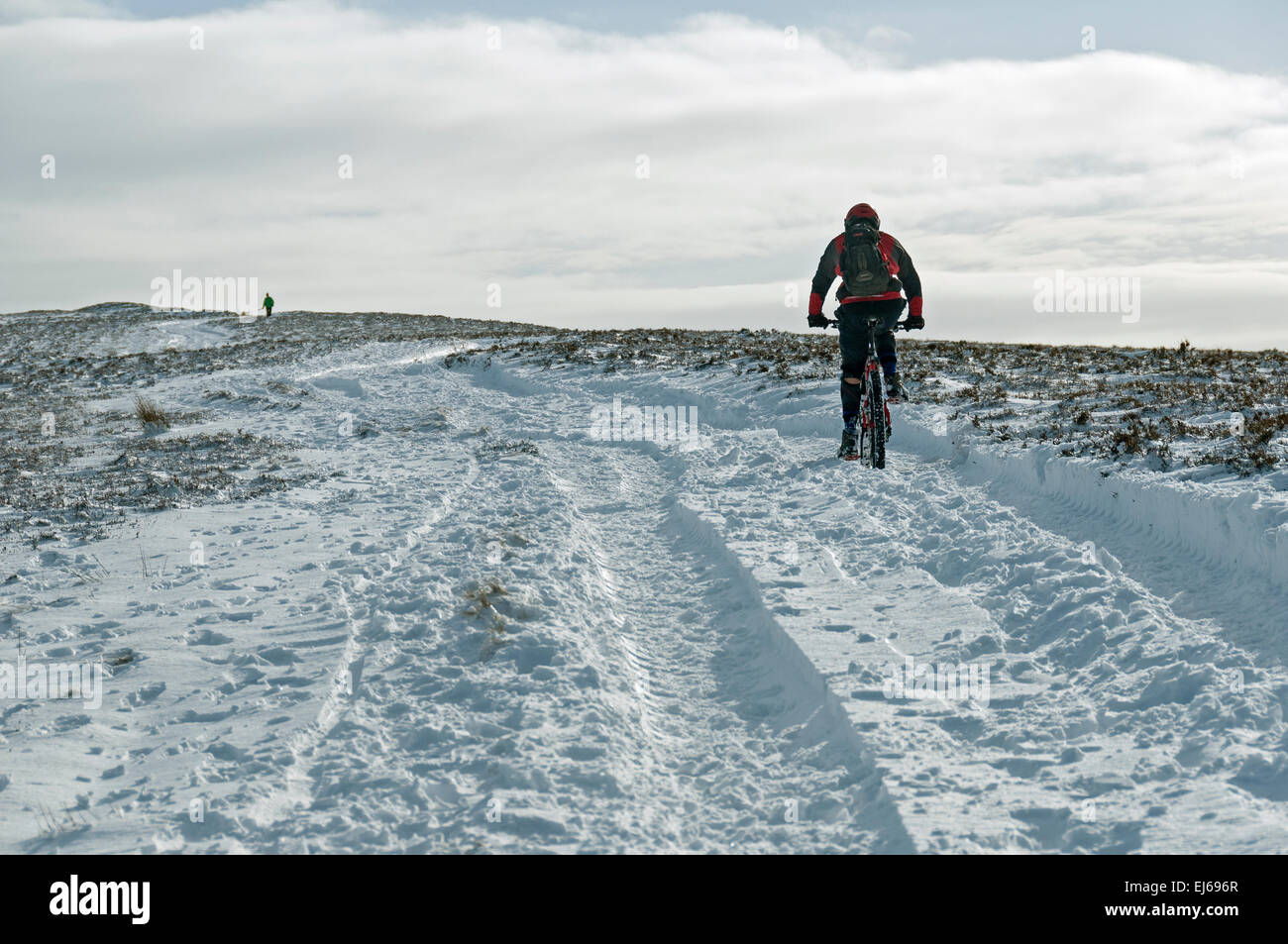 Mountain Biker dirigendosi verso Win Hill in inverno, Peak District, Derbyshire, Inghilterra, Regno Unito. Foto Stock