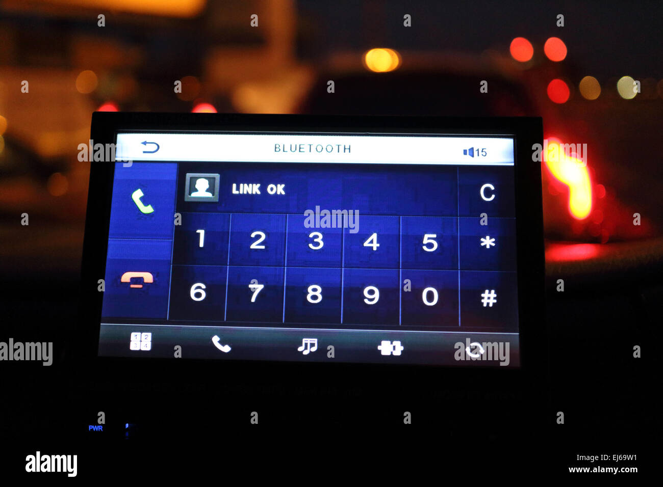 Telefono cellulare bluetooth nella schermata di collegamento nel cruscotto del veicolo nel traffico di notte Foto Stock