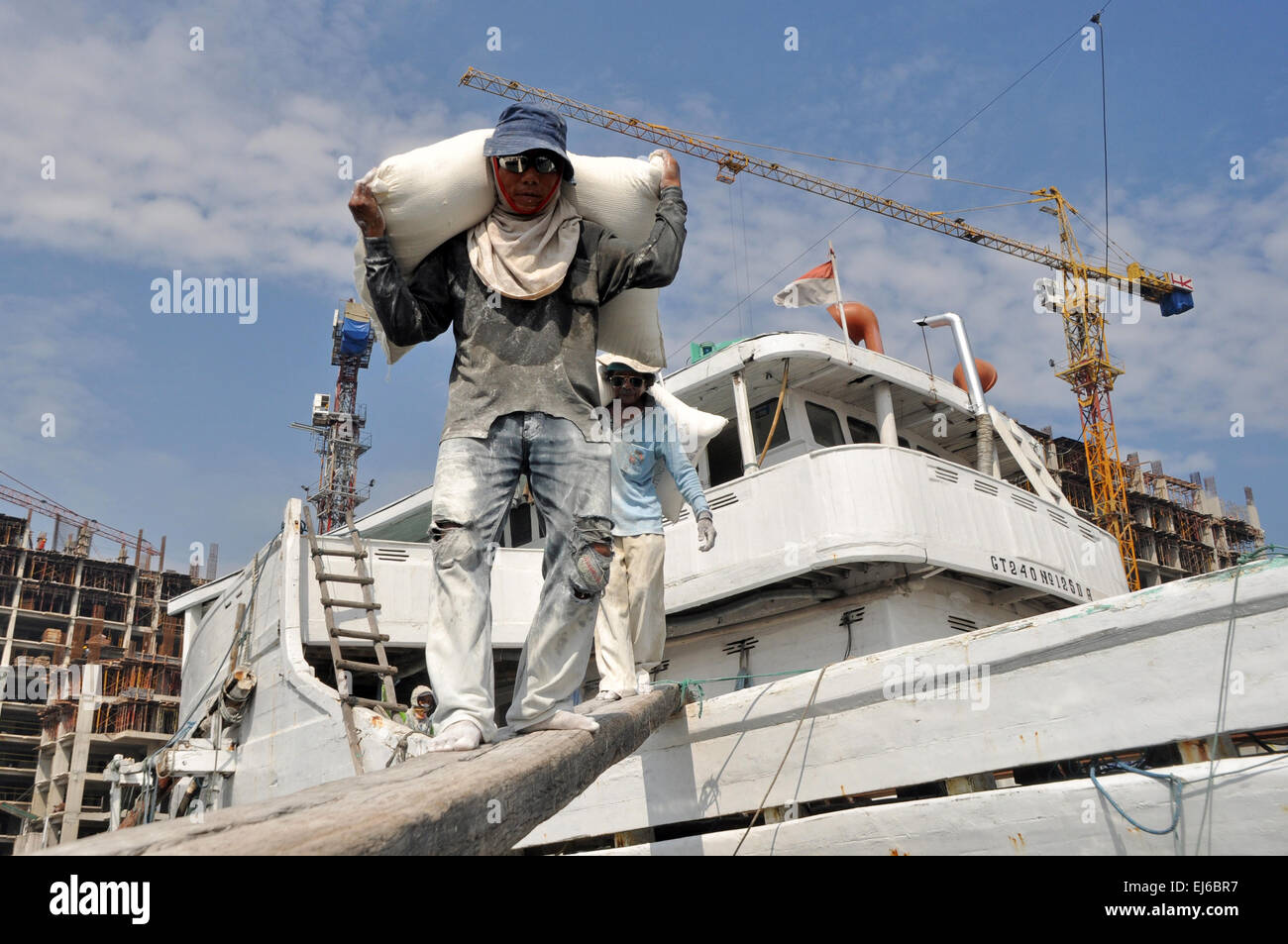 Abourers indonesiano lo scarico dei sacchi di farina dalla nave al Porto di Sunda Kelapa a Jakarta, Indonesia. Le navi provenienti da molte regioni di Indonesia come il Borneo (Kalimantan), Sumatra e Sulawesi, e portano i prodotti agricoli a Jakarta. Quando le navi phinisi tornare a casa loro, essi portano i materiali da costruzione come acciaio, cemento, ecc. Foto Stock