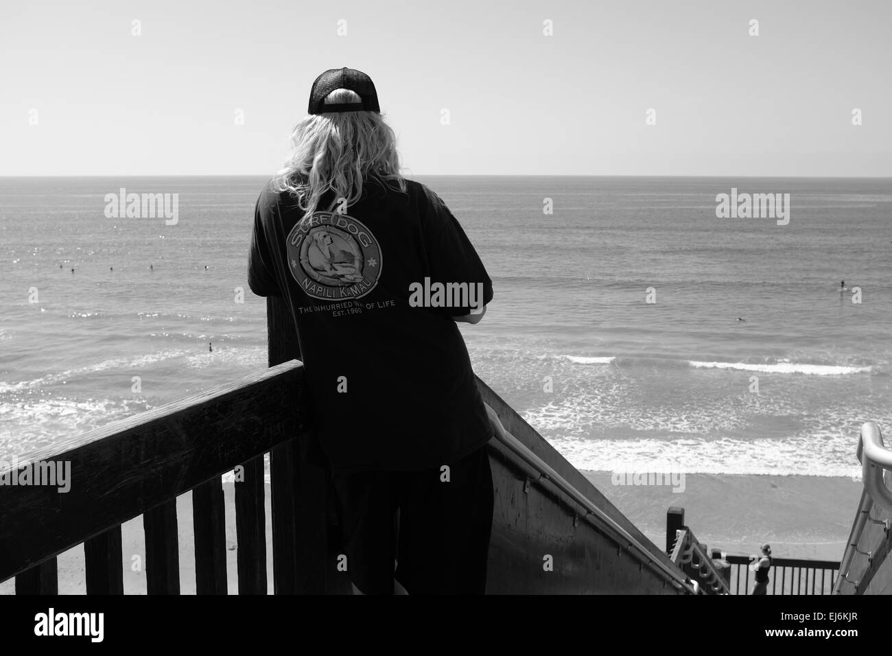 Accesso alla spiaggia Grandview a Encinitas, California, surfista più anziano con cappello a sfera e camicia con didascalia Surf Dog, guardando il surf Foto Stock