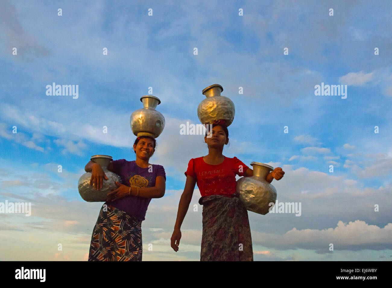 Le ragazze che trasportano giare di acqua nel villaggio di pescatori, Sittwe, Stato di Rakhine, Myanmar Foto Stock