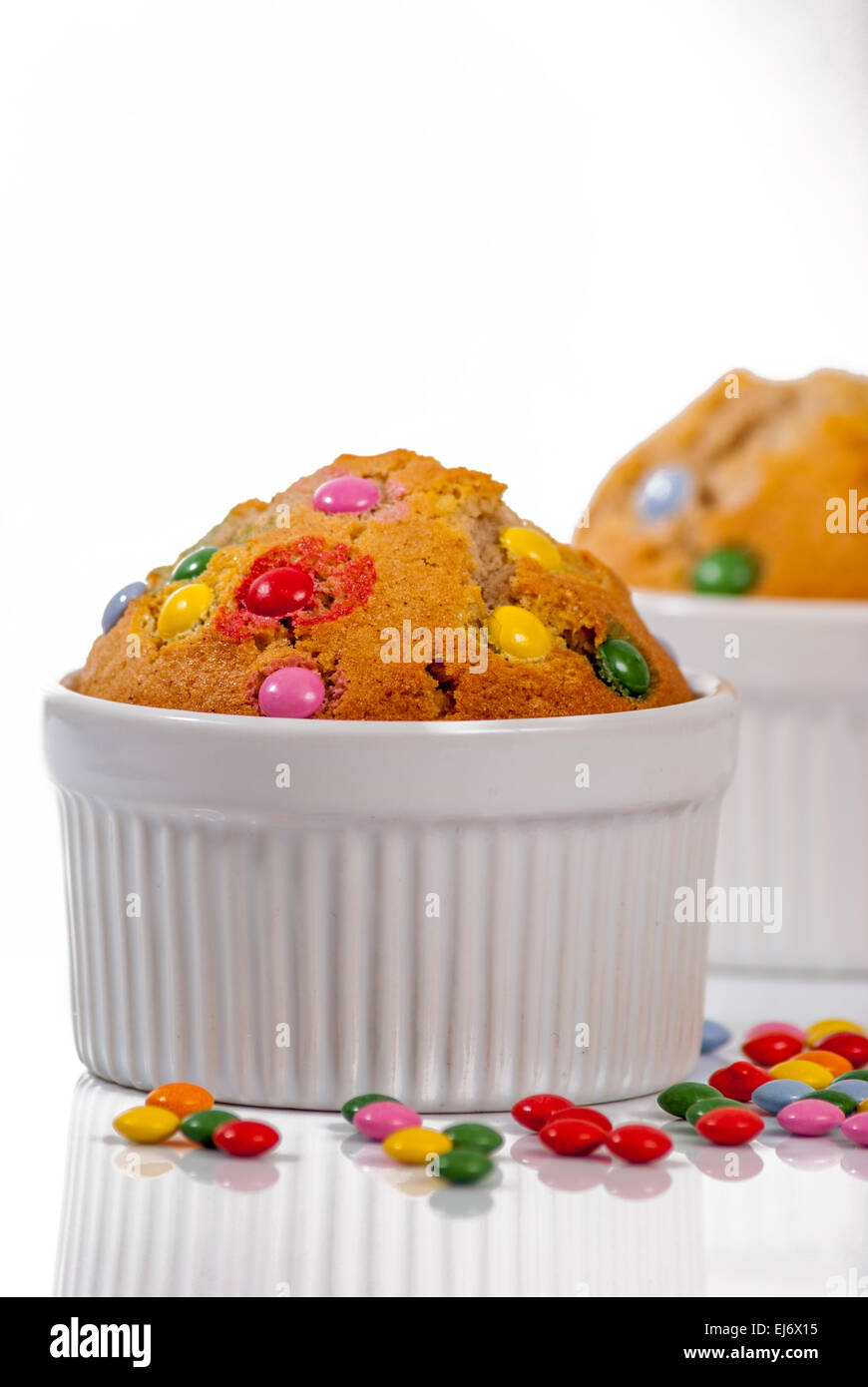 Muffin nella tazza bianca con caramelle a riflettere sullo sfondo Foto Stock