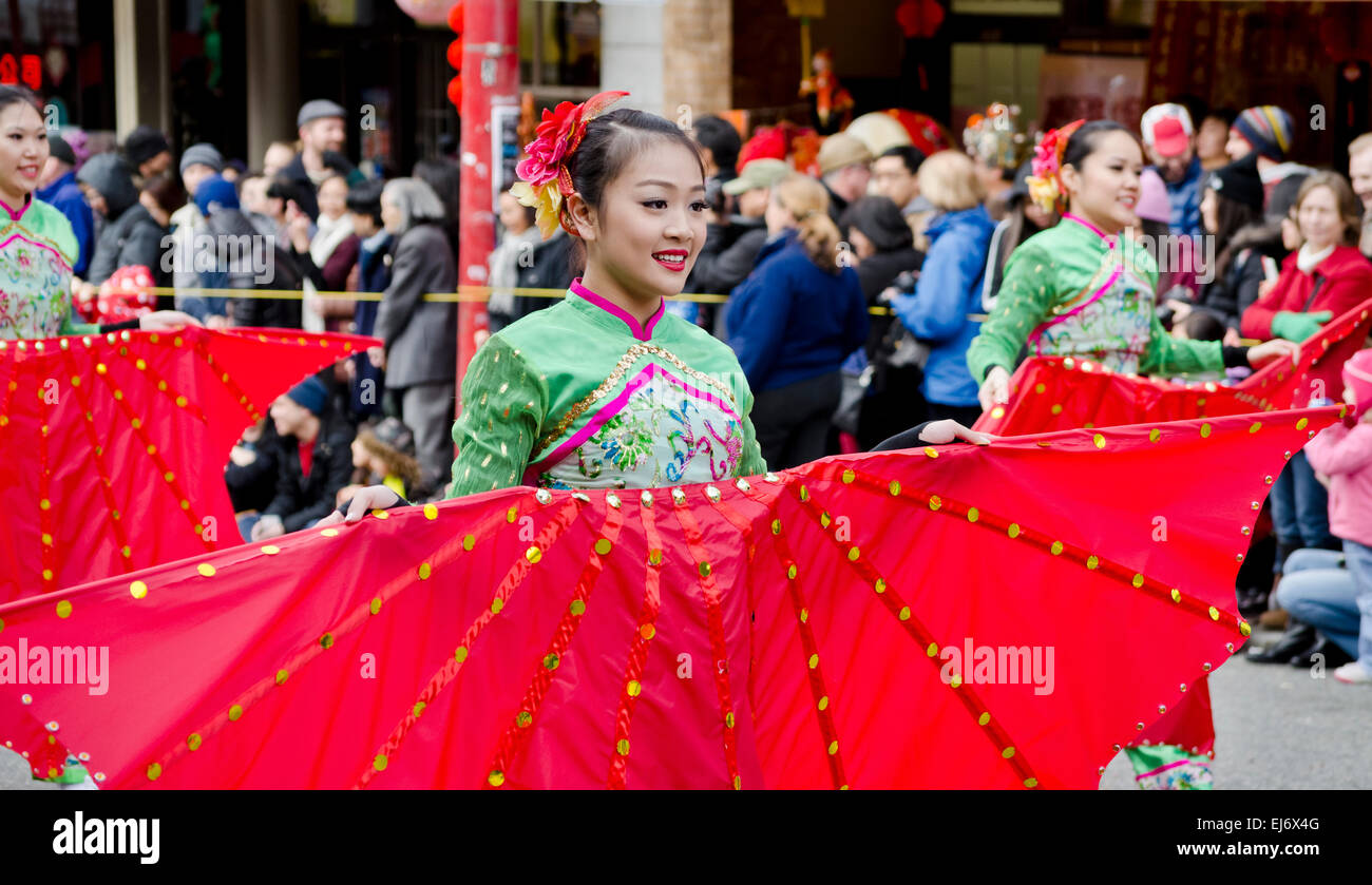 Donna asiatica esecutori che trasportano grandi fan di rosso che prendono parte al capodanno nuovo anno lunare's Parade in Chinatown a Vancouver in Canada Foto Stock