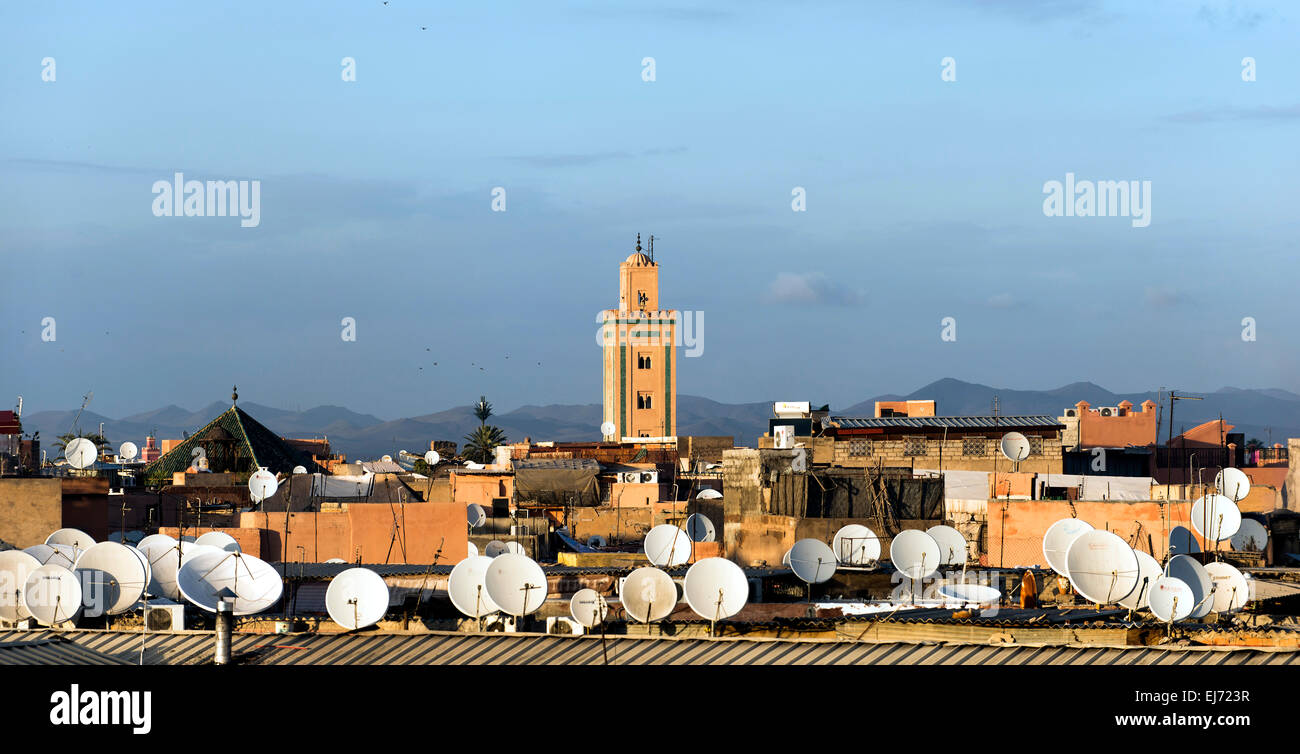 Vista attraverso i tetti con antenne satellitari per un minareto e monti Atlante, Marrakech, Marocco Foto Stock