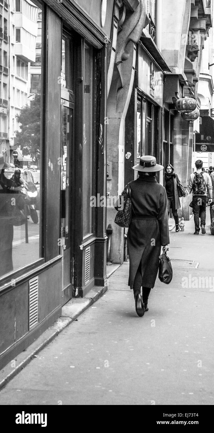 Un parigino chic donna in un bel cappotto e hat con buona qualità sacchetti passeggiate attraverso le strade del Marais appena dopo il lavoro. Foto Stock