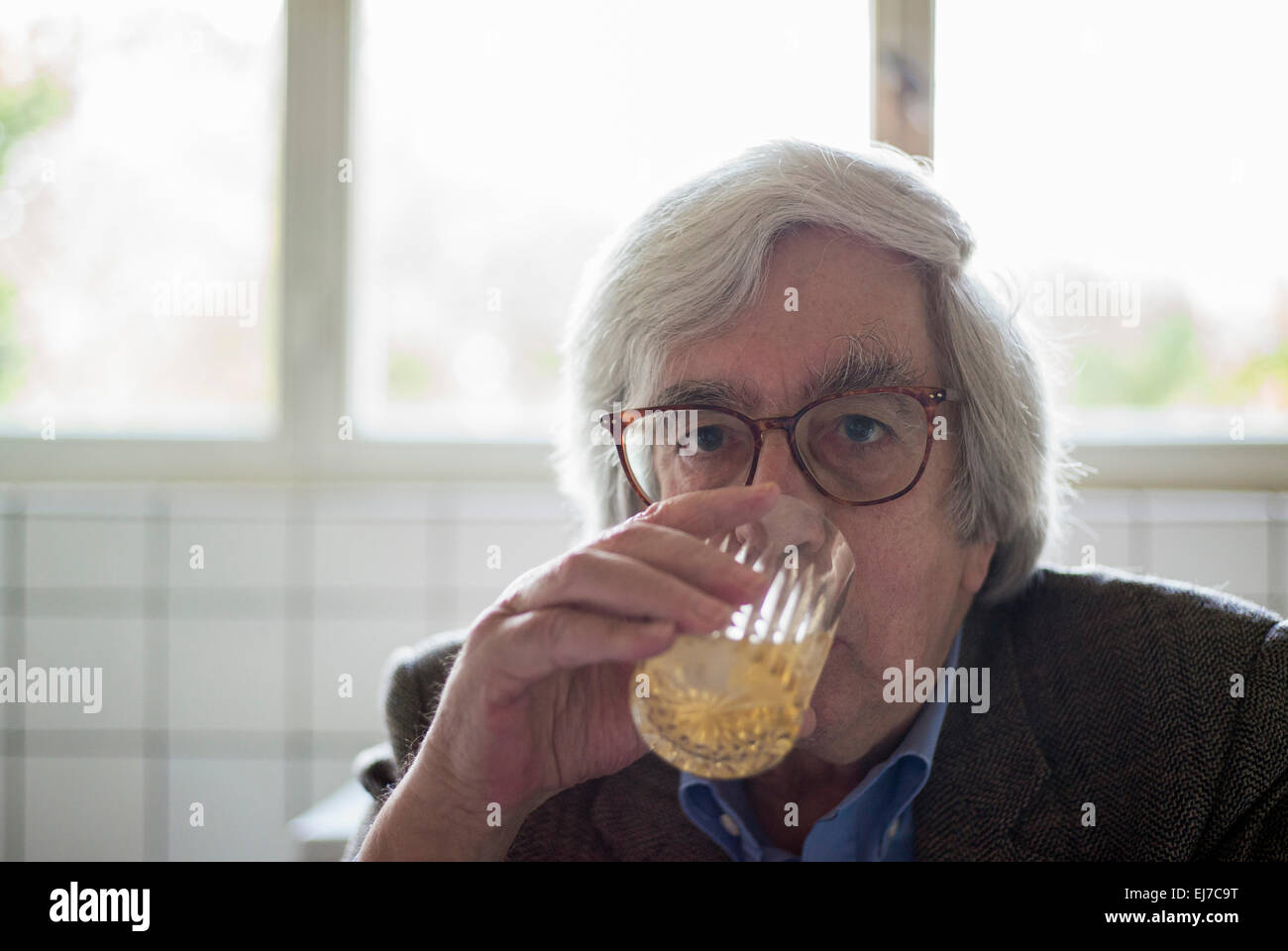 70s uomo anziano bere il succo d'arancia Foto Stock
