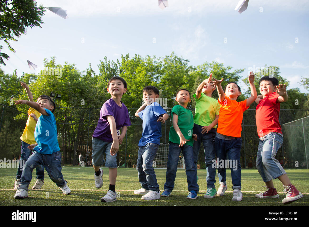 I bambini giocano un aeroplano di carta in erba Foto Stock