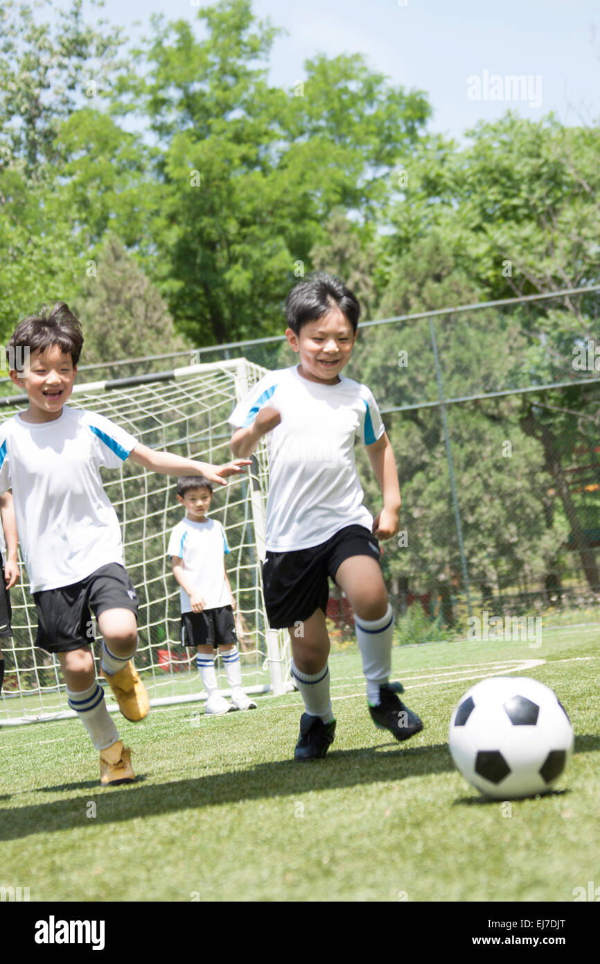 I ragazzi che giocano a calcio nel parco giochi Foto Stock