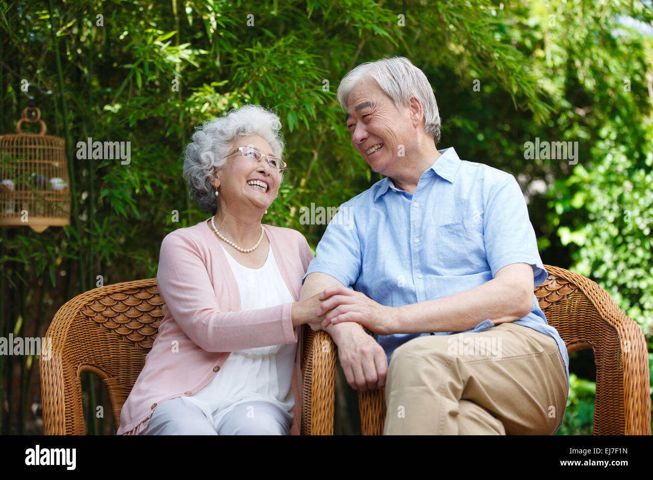 La vecchia coppia seduta su una sedia in giardino Foto Stock