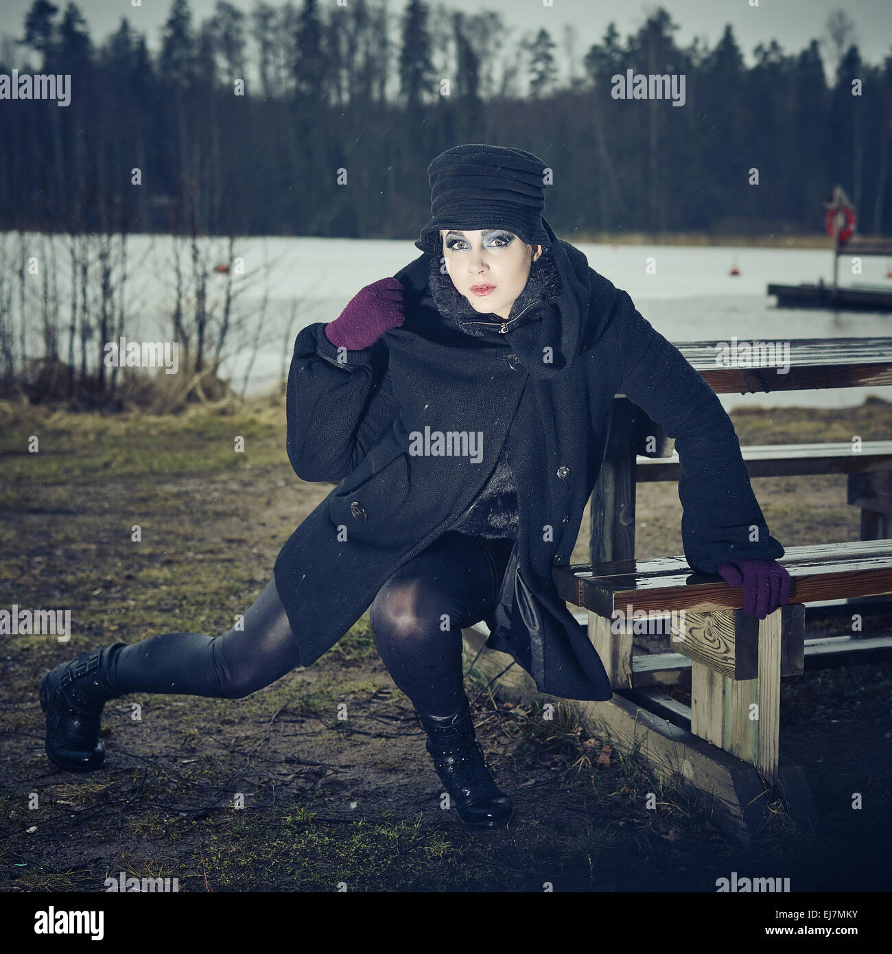 Weird moda donna che indossa un cappotto invernale e hat e lei in posa di una spiaggia invernale, freddo pioggia, croce immagine elaborata Foto Stock