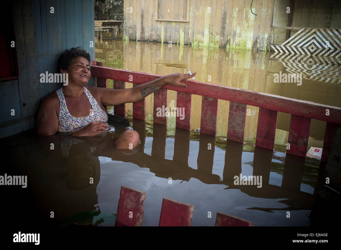 2015 Inondazioni in Amazzonia brasiliana - allagata casa nel distretto di Taquari, Rio Branco città, Acre. Francisca Chagas dos Santos poggia e fuma una sigaretta nel balcone del figlio house durante una pausa della pulizia e servizio di lavaggio. Persone pulire le pareti ed i soffitti di case inondate con il fiume di acqua di sporco prima di BBI perché non vi è alcun rifornimento d'acqua. Le inondazioni sono state che colpisce migliaia di persone in stato di Acre, nel nord del Brasile, dal 23 febbraio 2015, quando alcuni dei suoi fiumi, in particolare il fiume acri, in overflow. Foto Stock