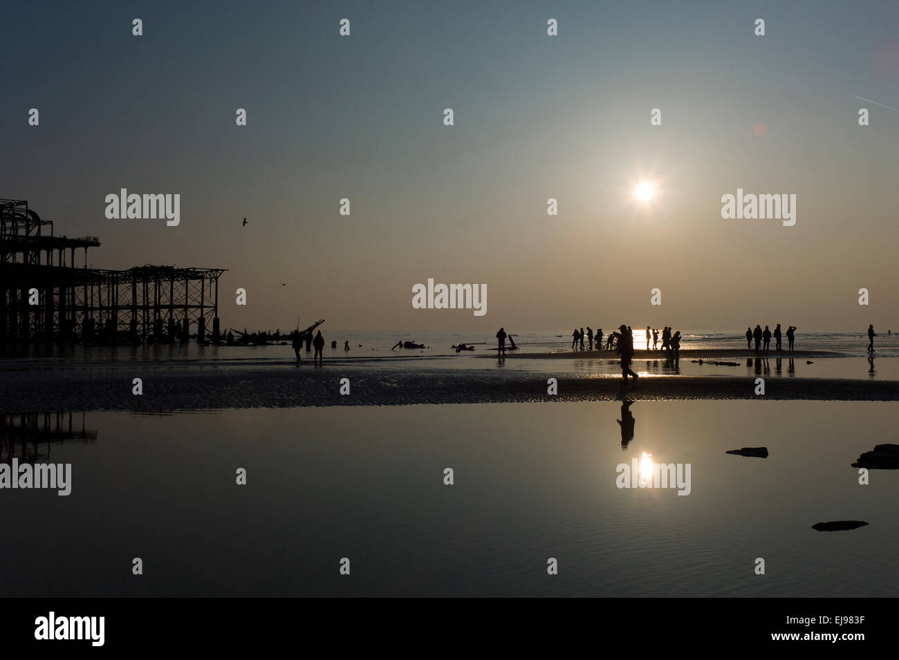 La gente sulla spiaggia e con il minor numero di marea dell'anno, abbandonata Molo Ovest di Brighton,,tramonto, silhouette Foto Stock