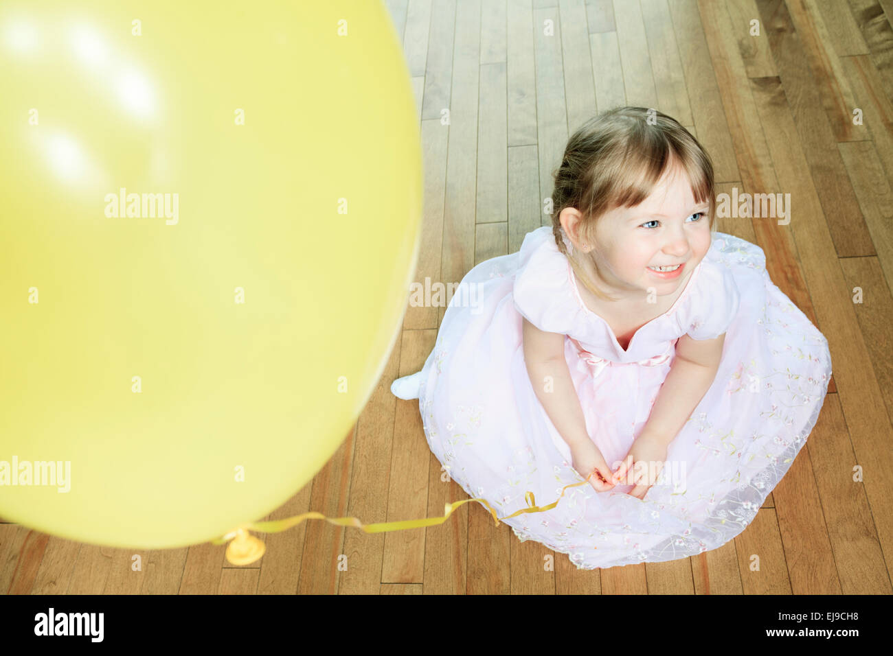 Una bella bambina Siediti sul pavimento con un palloncino Foto Stock