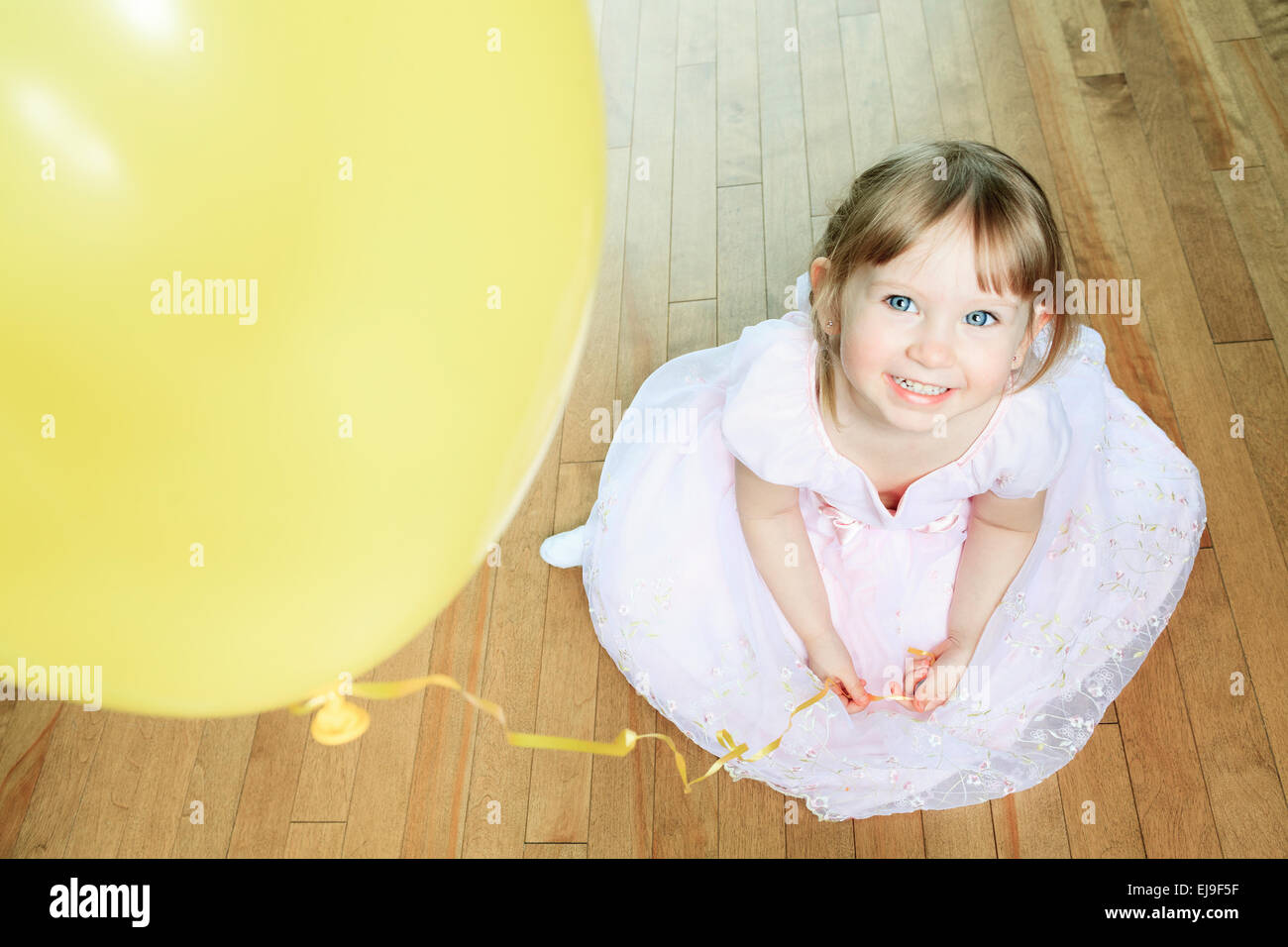 Una bella bambina Siediti sul pavimento con un palloncino Foto Stock