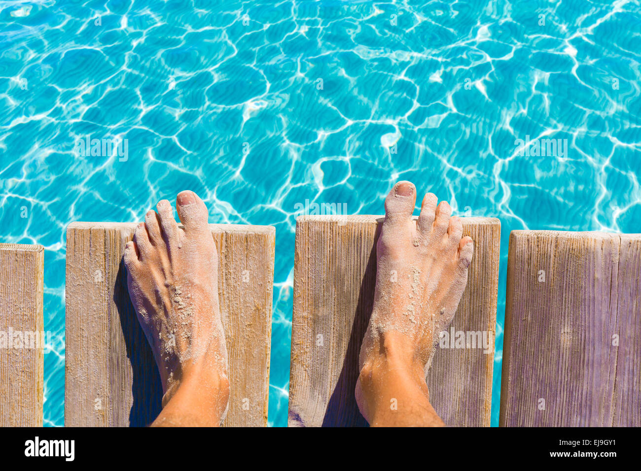 Piedi di sabbia sul molo sotto tropicale acqua turchese mare Foto Stock