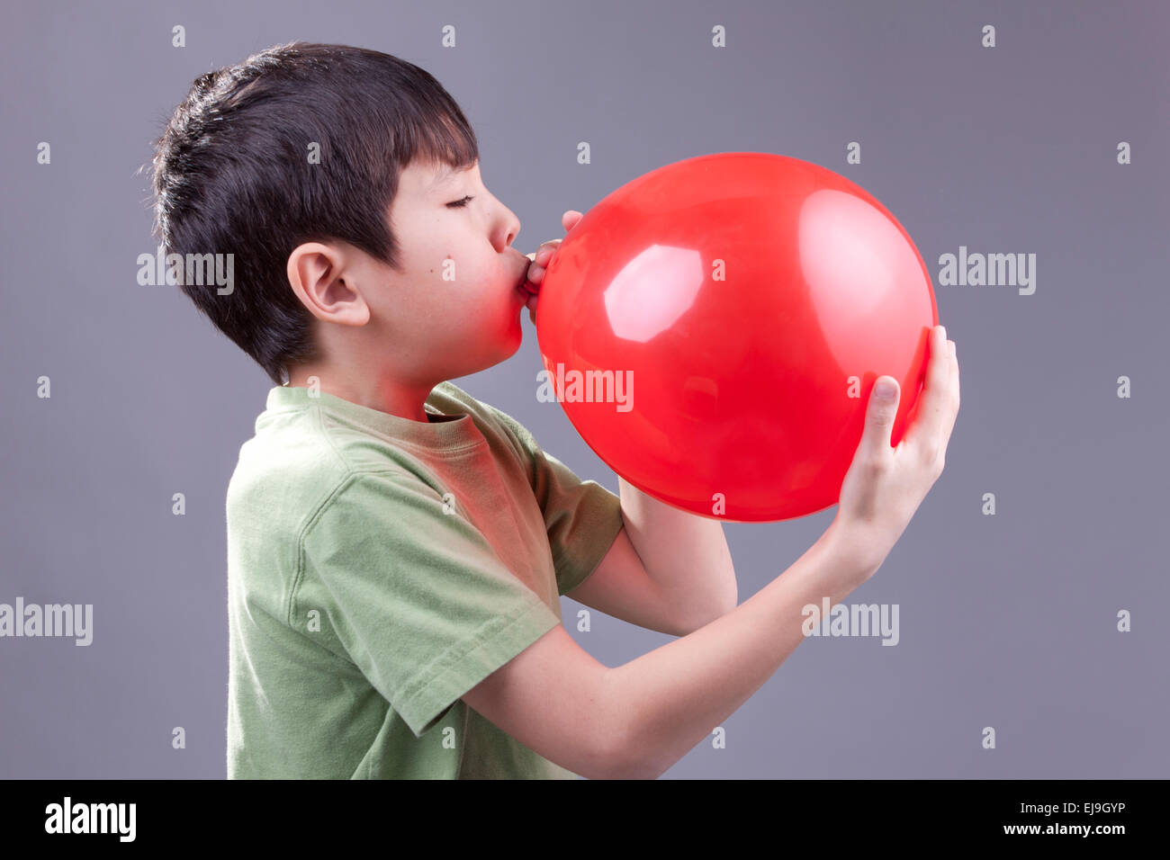 Un giovane ragazzo si brucia un palloncino rosso. Foto Stock