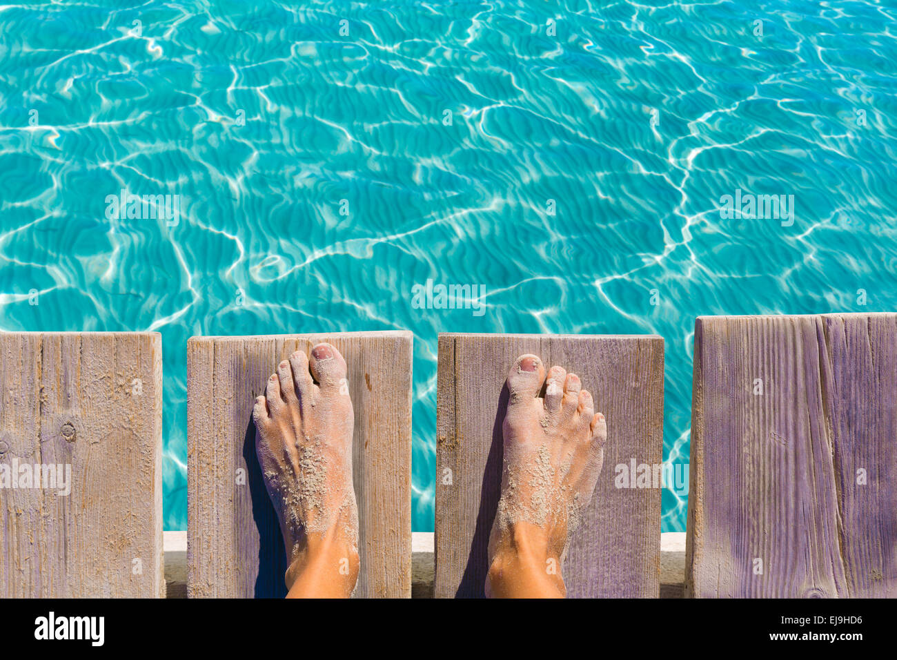 Piedi di sabbia sul molo sotto tropicale acqua turchese mare Foto Stock