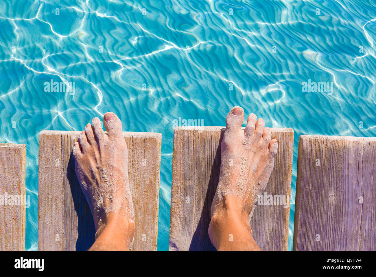 Piedi di sabbia sul molo sotto tropicale acqua turchese mare Foto Stock