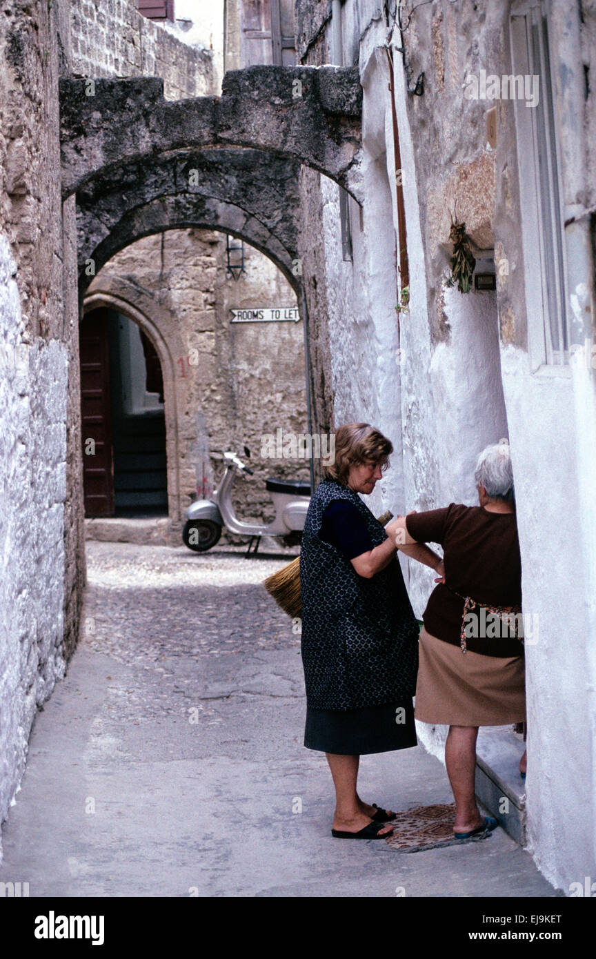Le donne greche o vicini di casa Chat sulle porte delle loro case  tradizionali a Rodi città vecchia di Rodi Grecia Foto stock - Alamy