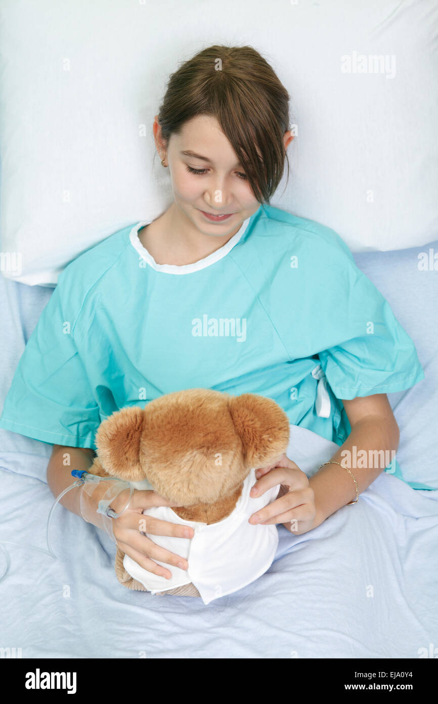 Piccola ragazza nel letto di ospedale con Teddy bear Foto Stock