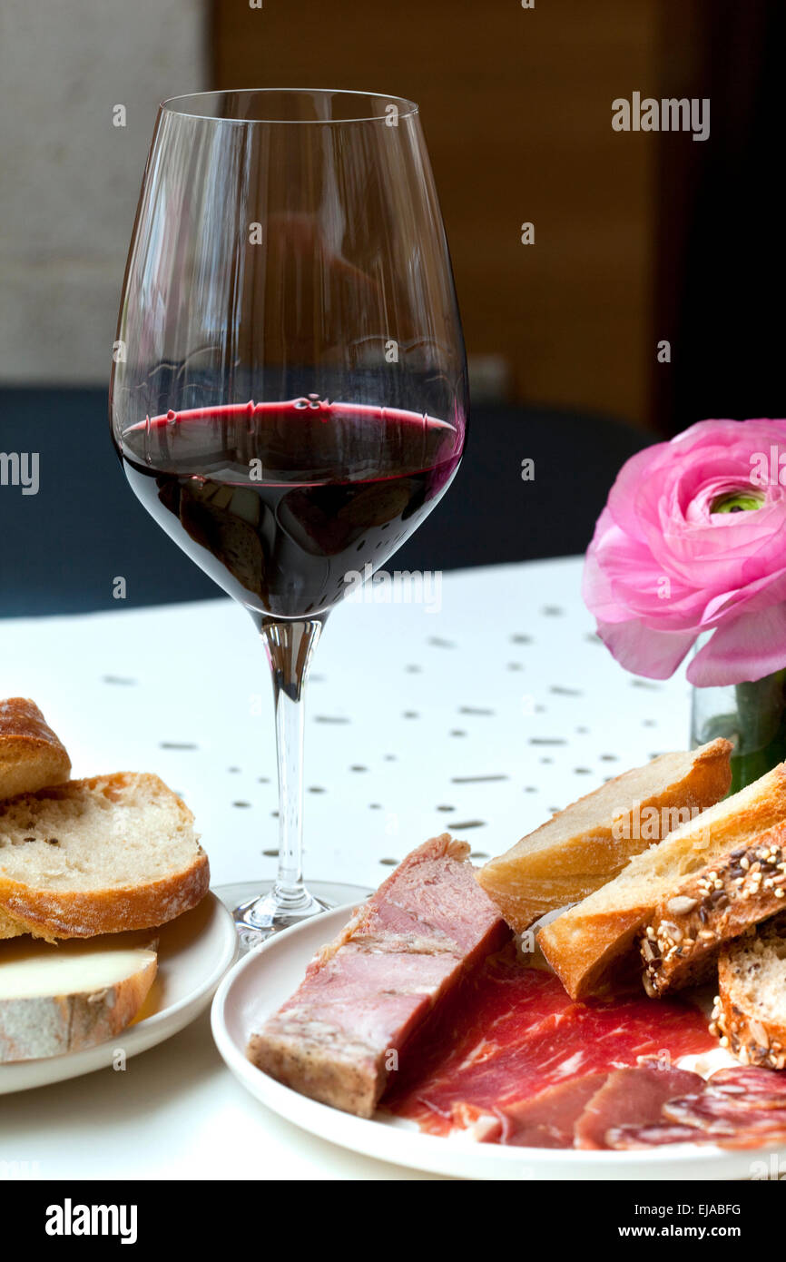 Bicchiere di vino rosso, carne fredda e pane su un tavolo Foto Stock