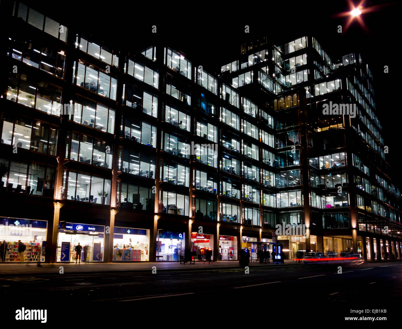 Illuminata luminosamente negozi e edificio per uffici di notte in Victoria Street a Westminster Londra Inghilterra REGNO UNITO Foto Stock