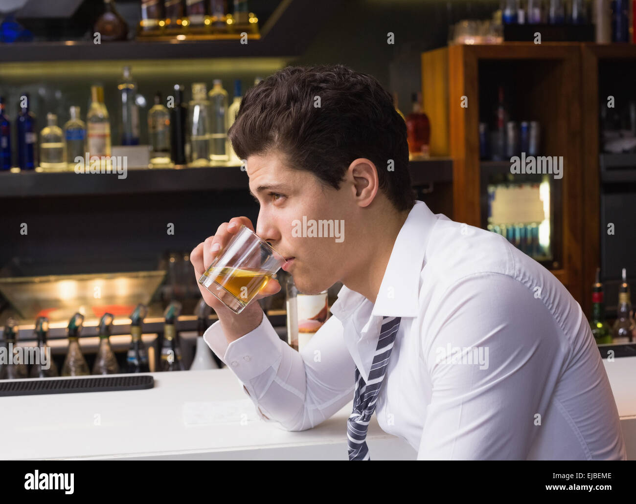 Giovane uomo di bere whisky neat Foto Stock