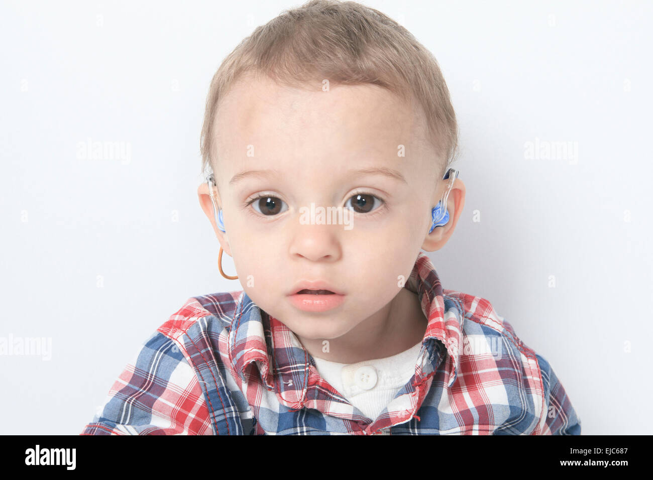 Un ragazzo con un apparecchi acustici su sfondo grigio Foto Stock