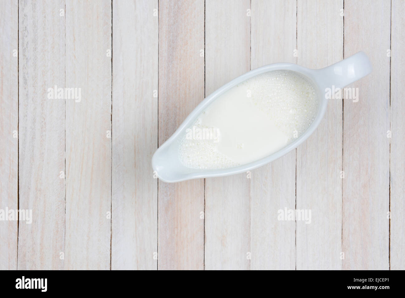 Scatto dall'alto di una brocca del latte su un dipinto di bianco in stile rustico tavolo da cucina. Formato orizzontale con copia spazio. Foto Stock