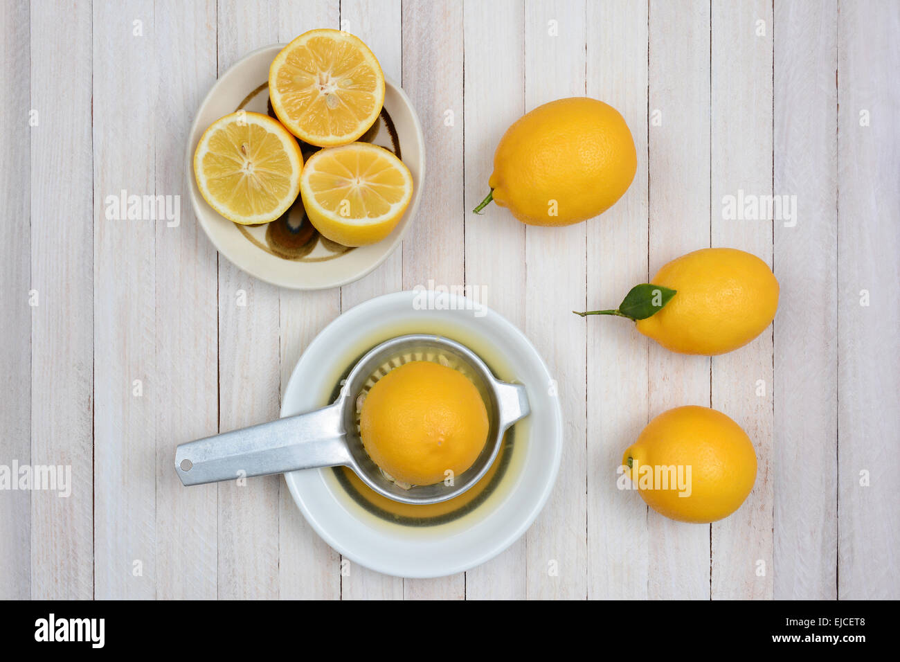 Spremitura limoni ancora vita girato da un angolo alto su un rustico di legno bianco tavolo da cucina. Foto Stock