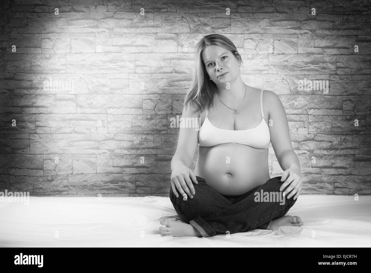 Bella donna incinta seduta sul letto Foto Stock