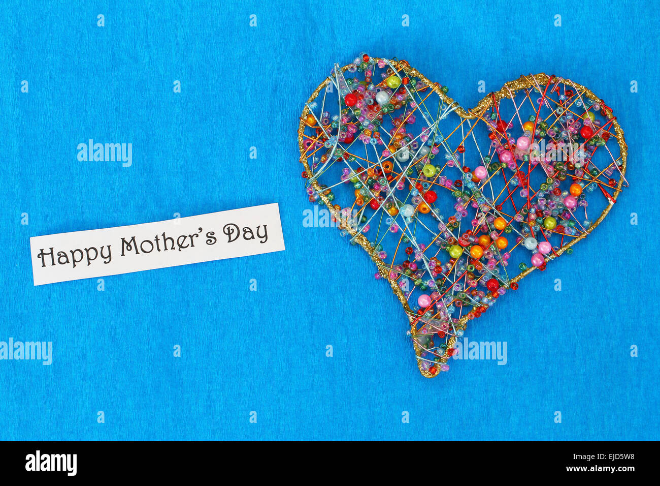 Felice Festa della mamma card con cuore di perline colorate su sfondo blu Foto Stock