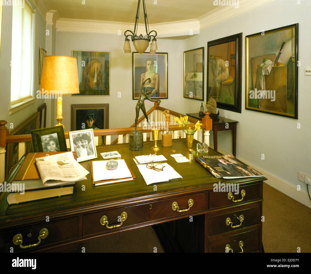 Cuoio e rabboccato antica scrivania in studio degli anni ottanta con gruppo di dipinti sulle pareti Foto Stock