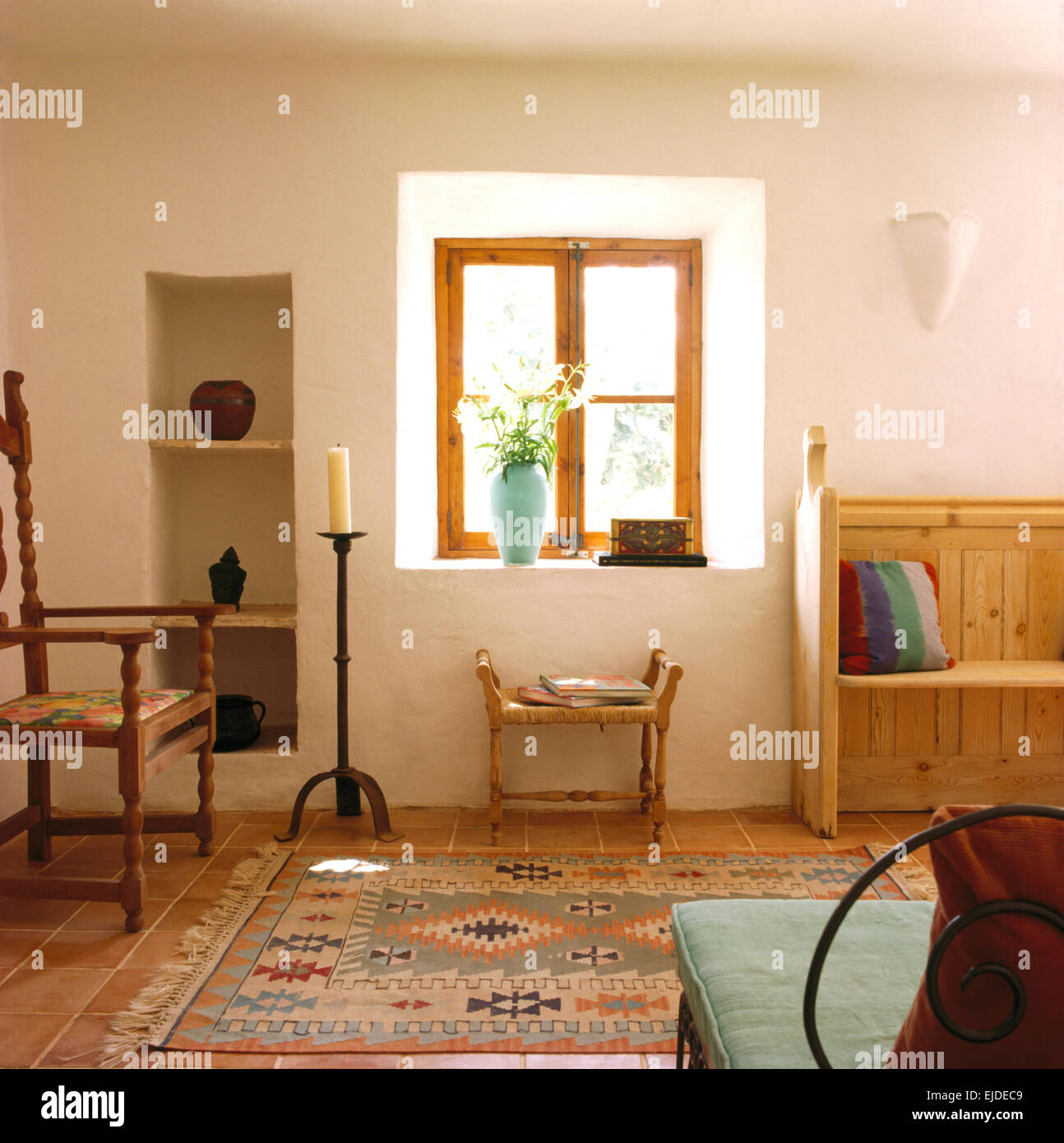 Arredamento semplice e tappeto a motivi geometrici in Maiorca rustica sala soggiorno con alcova scaffalatura Foto Stock