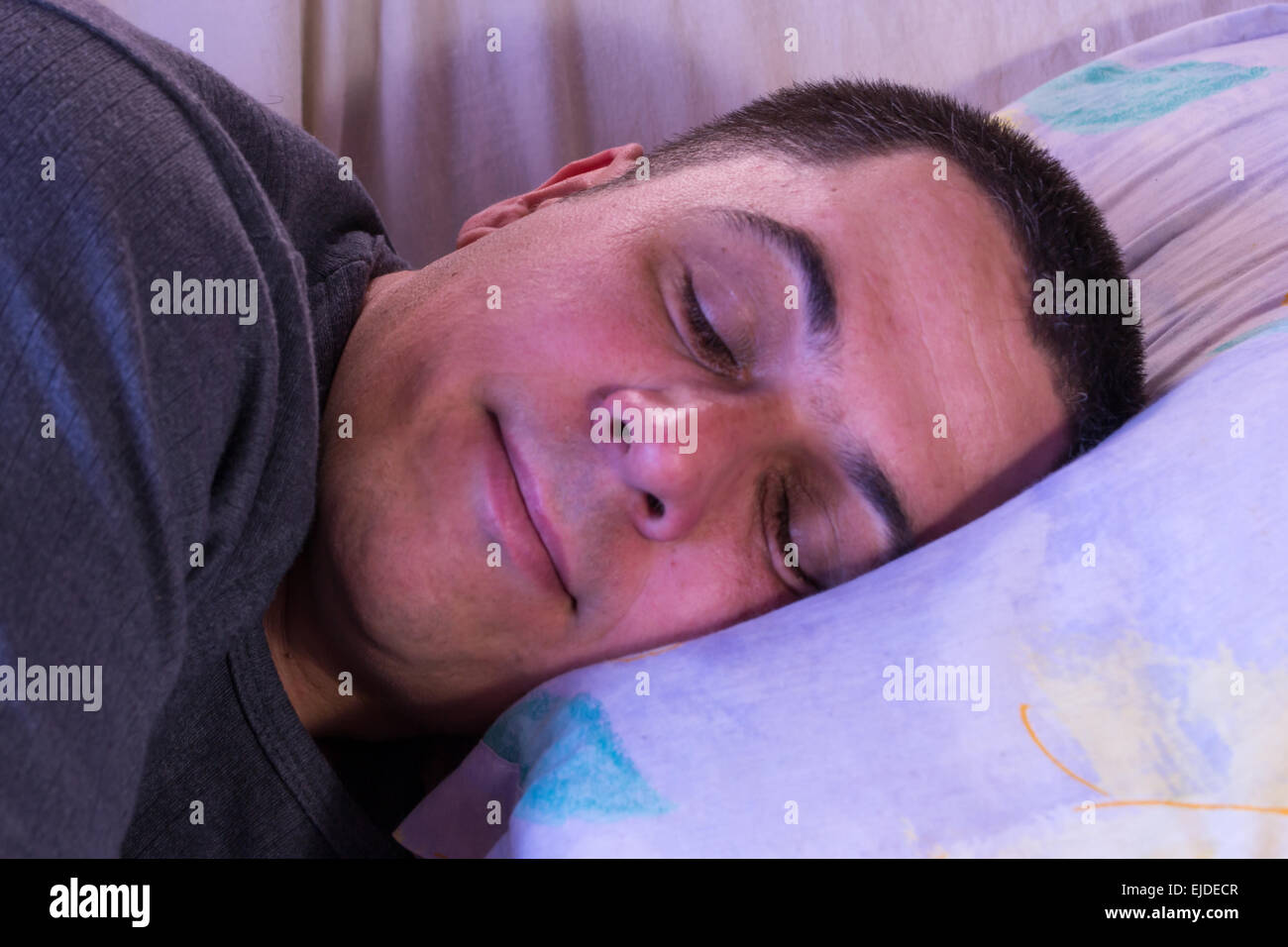 Un maschio caucasico di sorridere quando si dorme su un cuscino Foto Stock