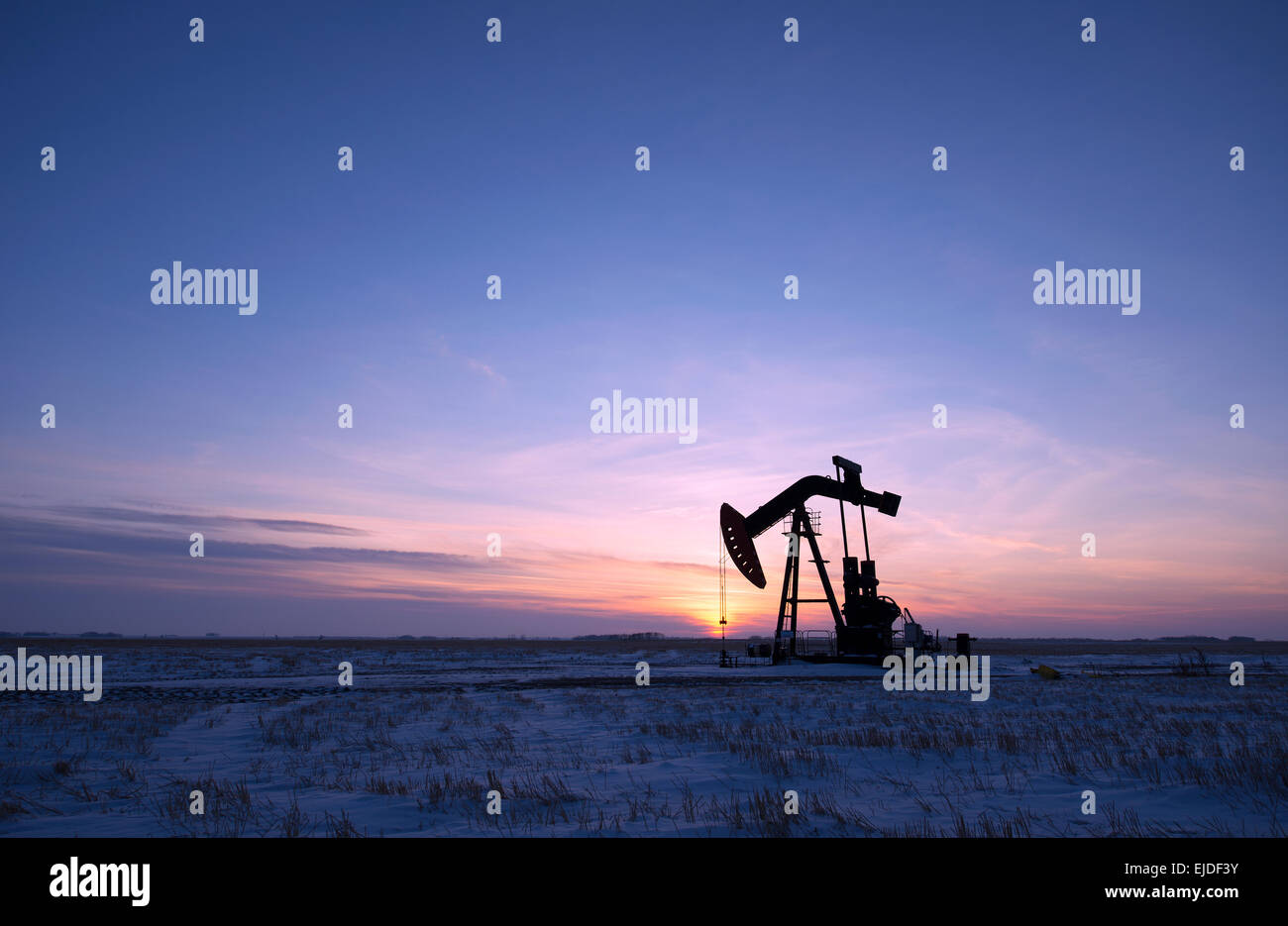 Un olio impianto di perforazione e pumpjack su una piana in canadese campi olio al tramonto. Foto Stock