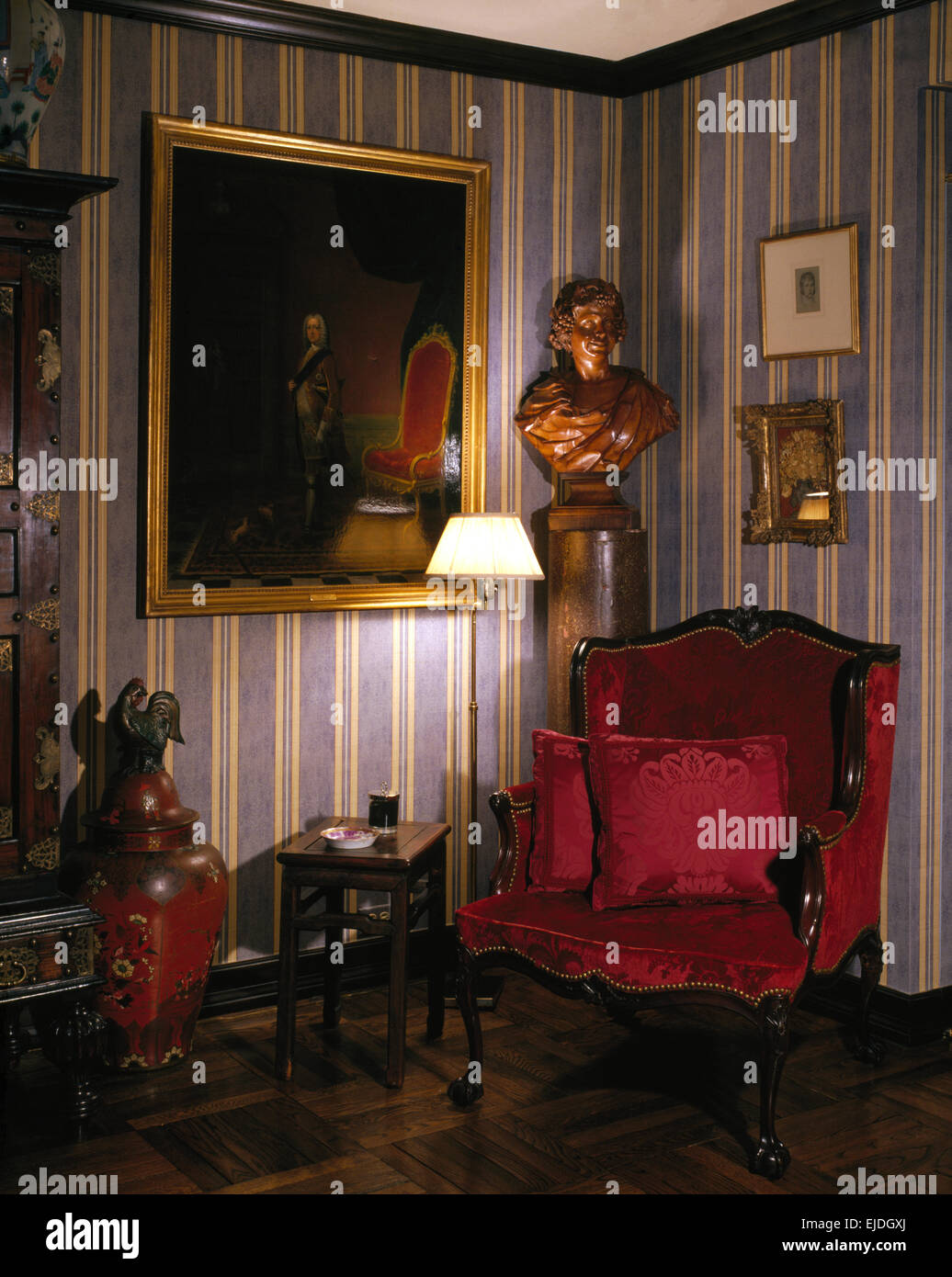 Grande pittura classica e busto in sala degli anni ottanta con velluto rosso imbottito sedia antica e carta da parati a strisce Foto Stock