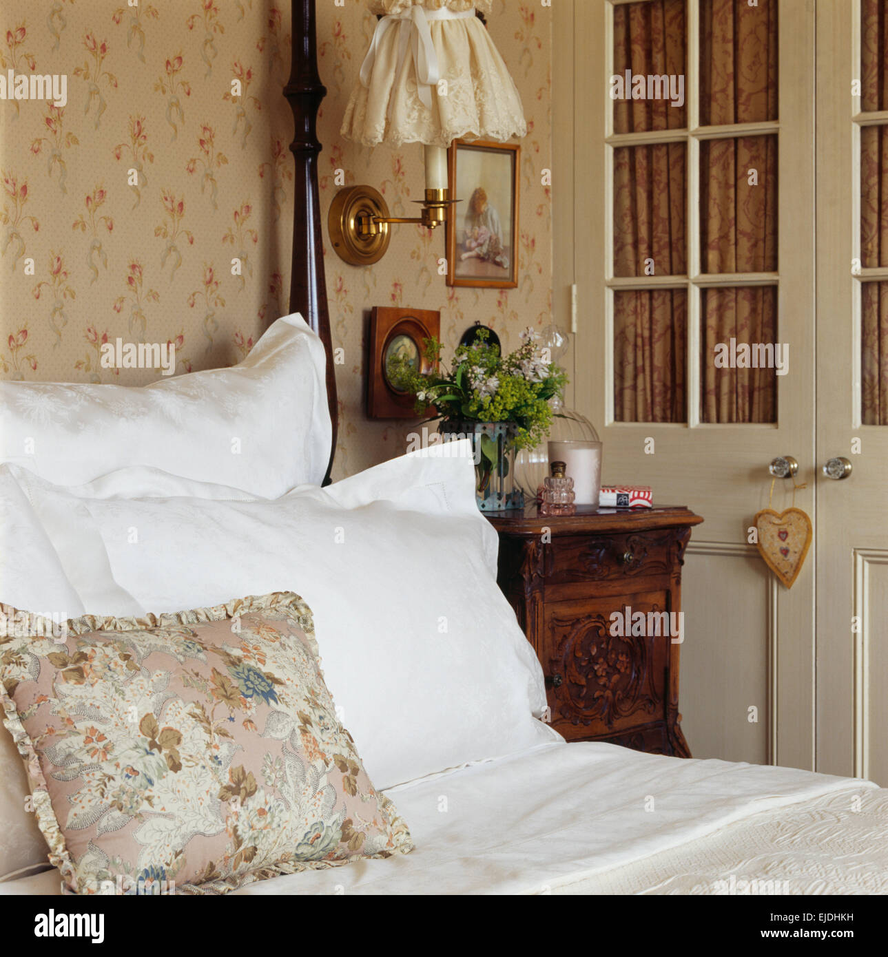 Close-up di un cuscino a motivi geometrici e cotone bianco cuscini sul letto in una camera da letto tradizionale con tende all'interno del armadio vetrato Foto Stock