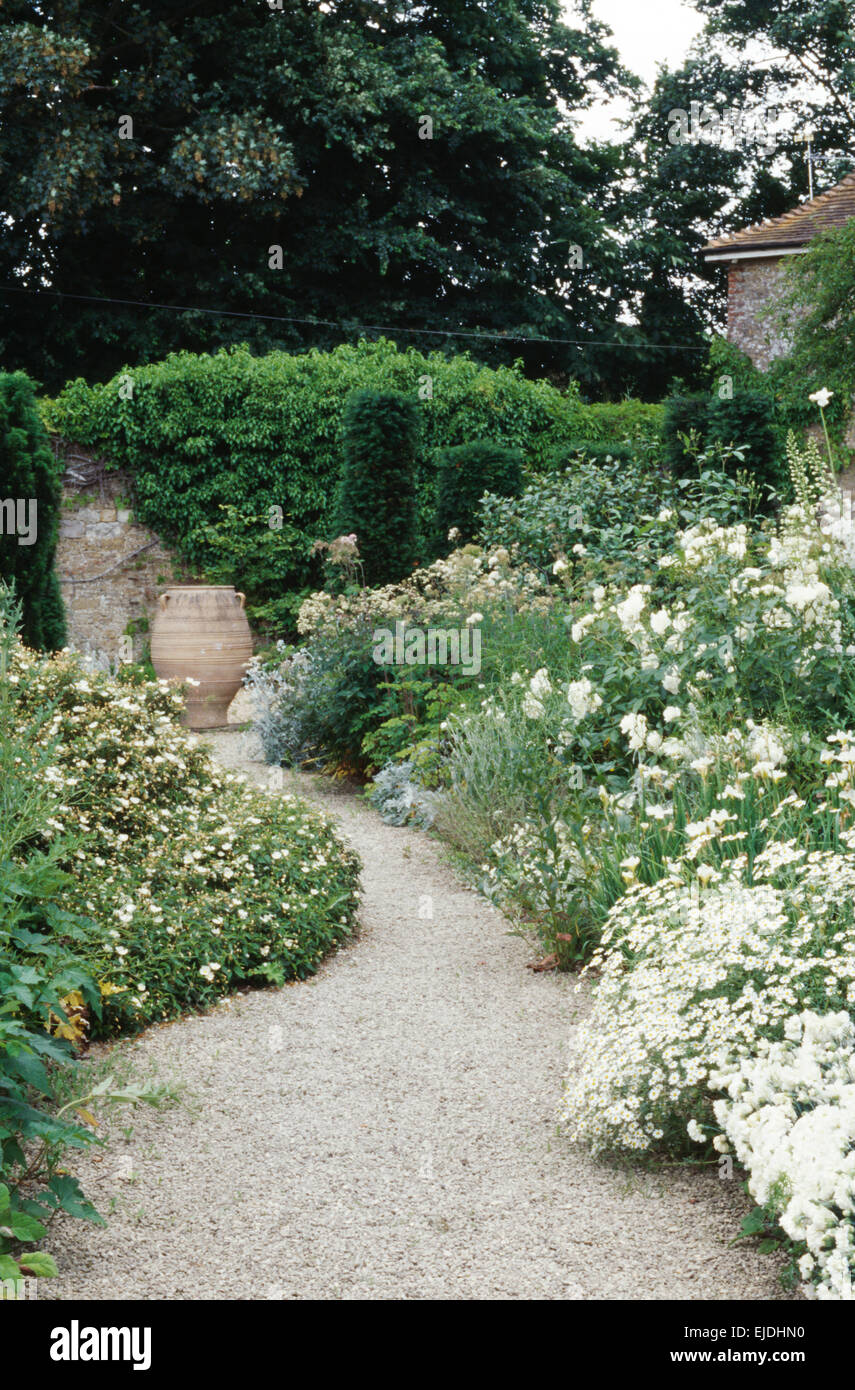 Sentiero di ghiaia attraverso frontiere con tutte le piante di bianco nel paese grande giardino in estate Foto Stock