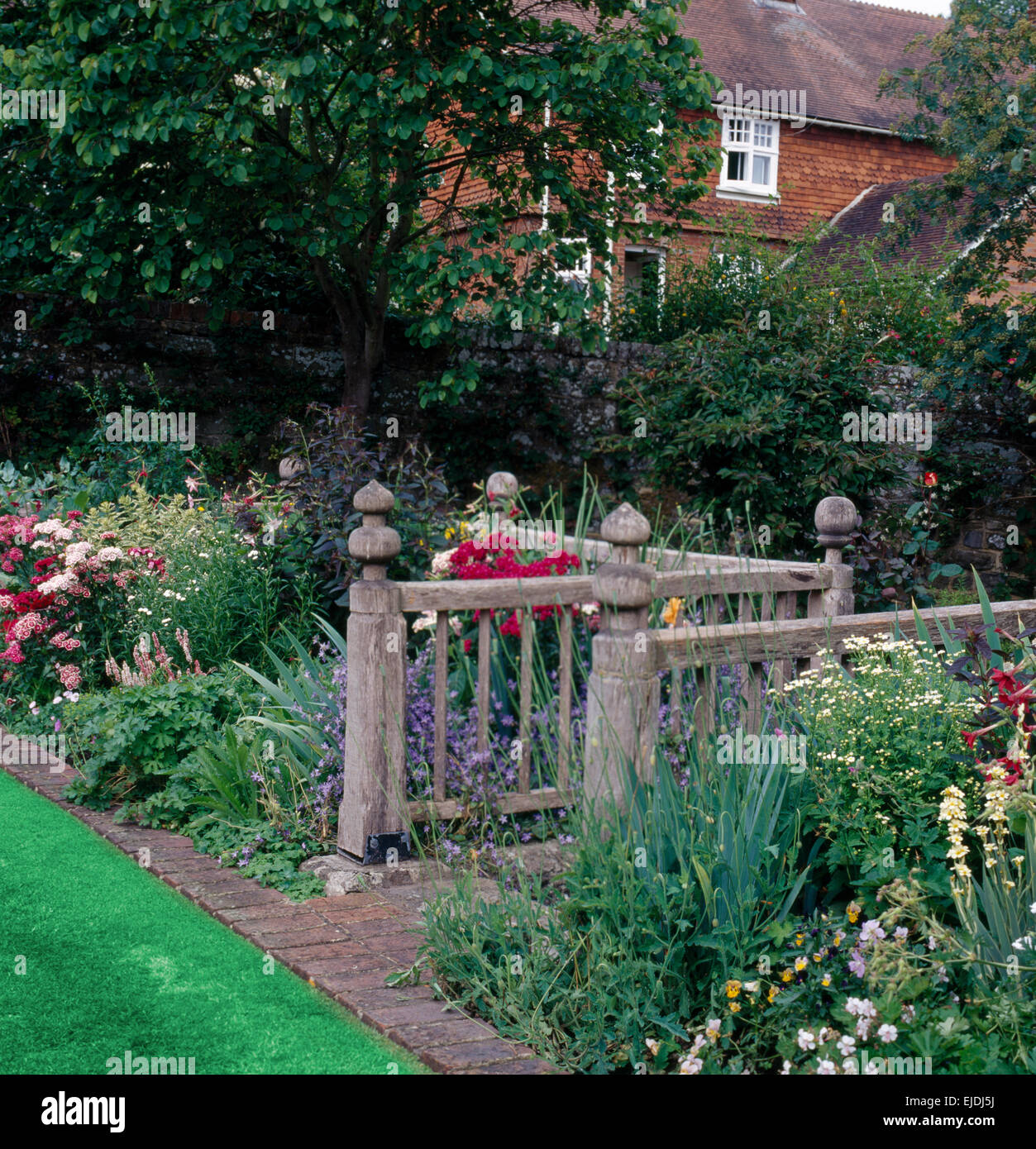 Recinzione in legno e il confine con coloratissime piante perenni in giardino di campagna in estate Foto Stock