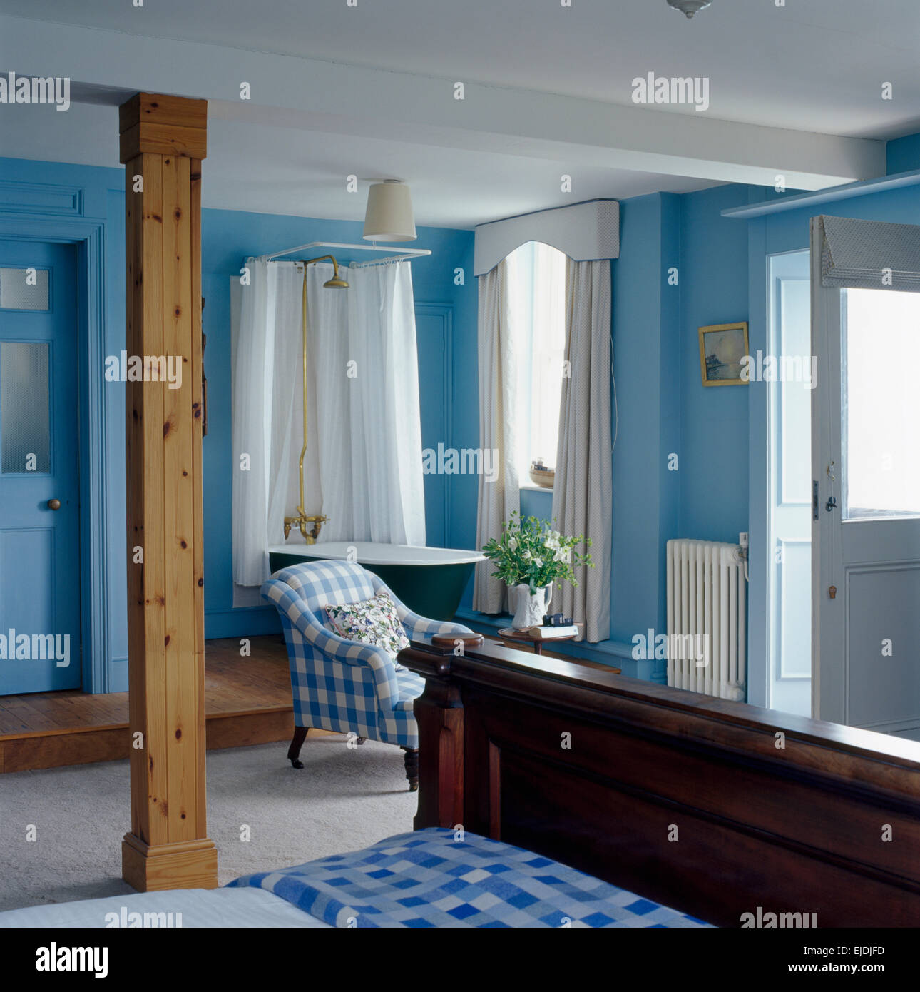 Montante trave di legno in costiera blu camera da letto con doccia sopra il rullo top bagno con drappi bianchi Foto Stock