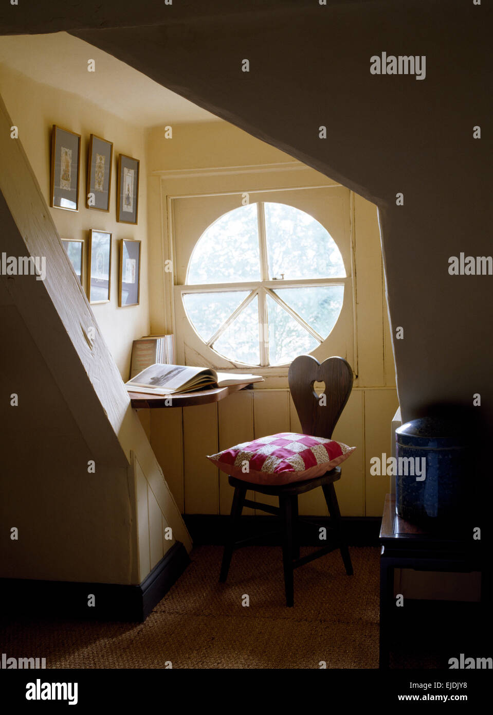 Finestra circolare nello studio per un angolo della camera da letto mansarda con cuscino patchwork rustico sedia in legno Foto Stock