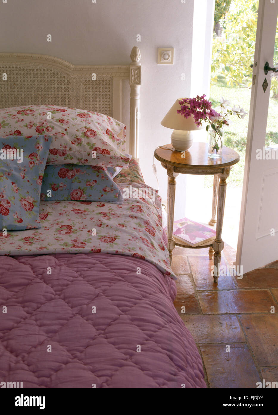 Rose modellato cuscini e piumini rosa sul letto nel paese francese camera da letto con piccolo comodino Foto Stock