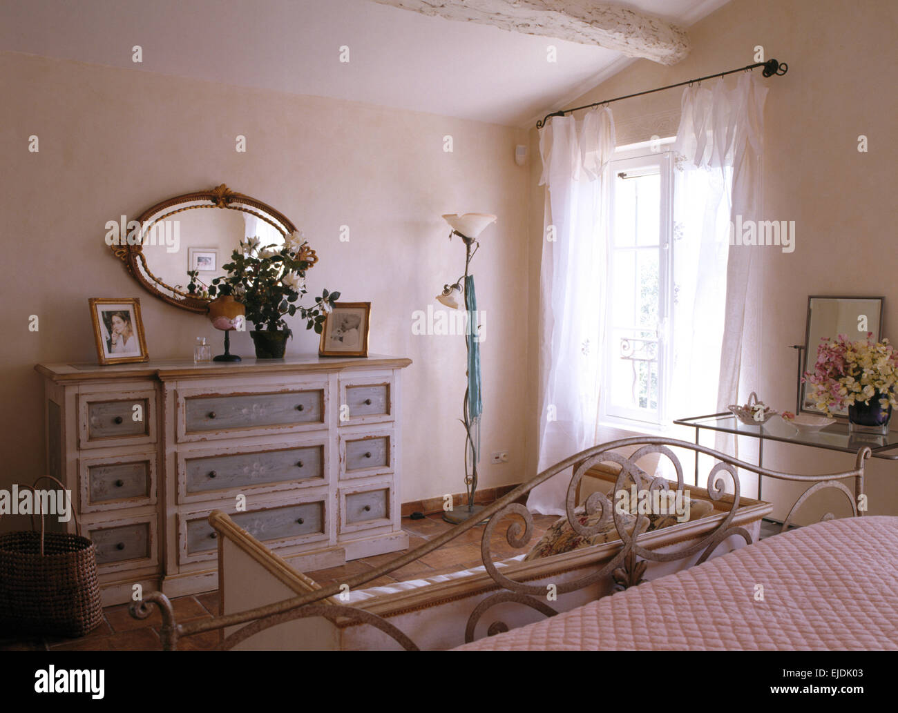Specchio ovale dipinto sopra cassettiera in paese francese camera da letto con il bianco voile tende alle finestre Foto Stock