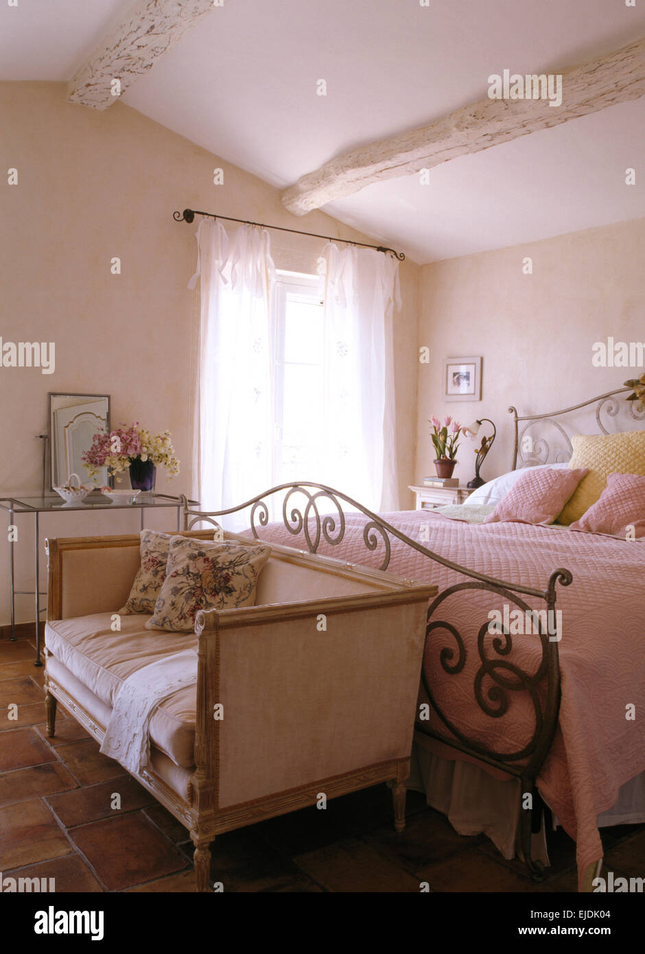 Piccolo divano ai piedi di ornati in ferro battuto letto nel paese francese camera da letto Foto Stock