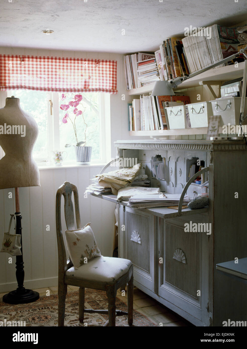 Adattare il manichino nella piccola sala di cucitura con armadio dipinto sotto ripiani Foto Stock