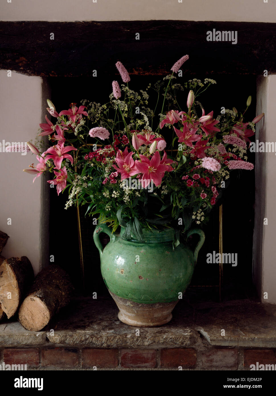 Still-Life di gigli rosa e persicaria con fiori d'estate in un rustico vaso verde Foto Stock