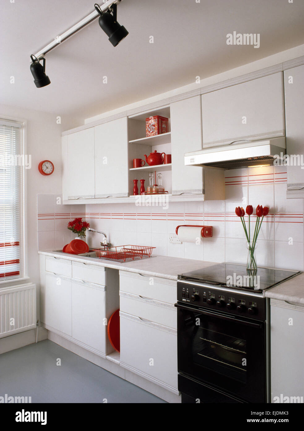 Nero di forno a gas in bianco degli anni ottanta cucina con dettagli rosso e illuminazione pista Foto Stock