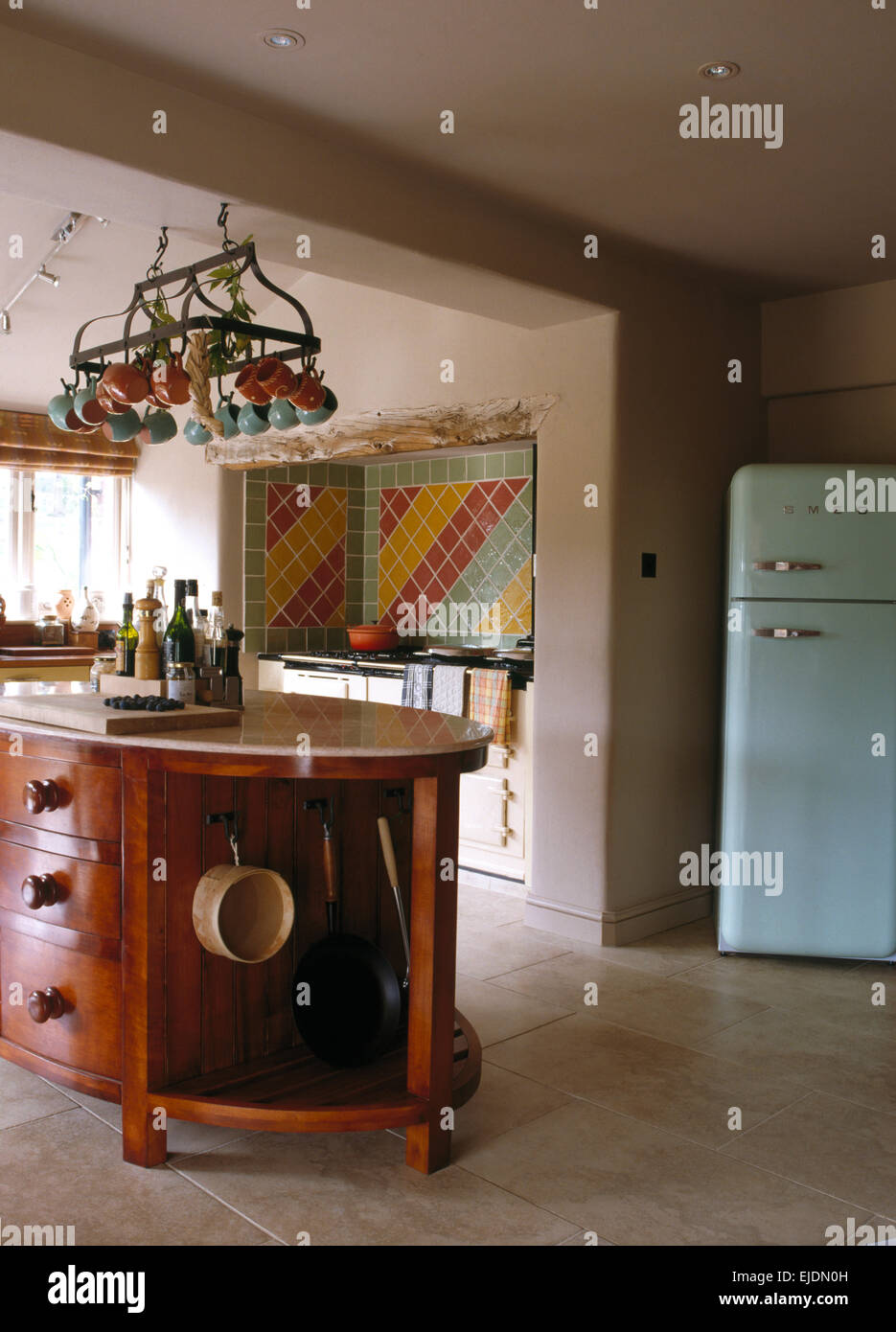 Tazze memorizzati su rack a soffitto sopra isola con unità di pan integrale dello storage in cucina con estensione blu pallido Smeg frigo Foto Stock